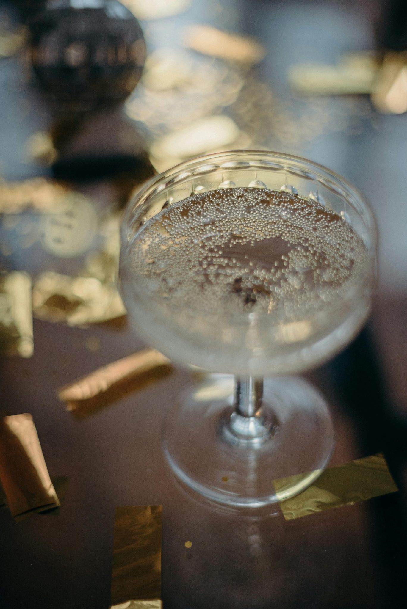 Champagne in a coupe glass surrounded by festive gold confetti, perfect for celebrations.